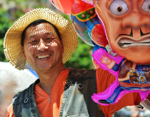 单位：九三学社昆明市委员会；作者：崔晓宏；标题《宜良花街节上的笑脸》；说明：宜良赶花街已有三百年的历史，每年一度的花街节热闹非凡，一个卖气球的男子脸上洋溢着灿烂的笑容