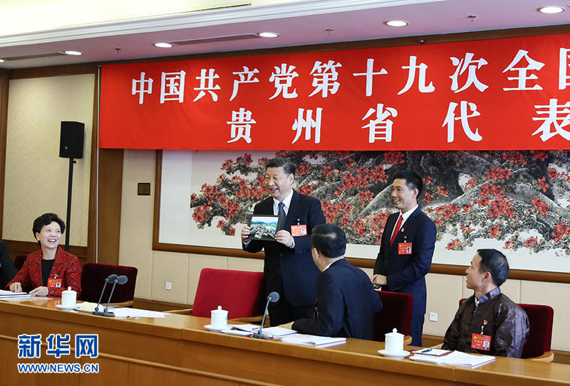 10月19日，习近平同志参加党的十九大贵州省代表团讨论。这是遵义市播州区花茂村党总支书记潘克刚将一幅鸟瞰村子新貌的照片送到习近平面前。习近平起身接过照片，边看边称赞：“这是风景画，很漂亮！”