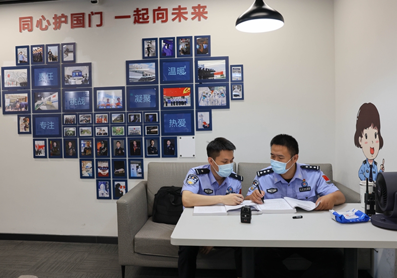 在首都机场3号航站楼边检执勤现场备勤室，两位移民管理警察在交流专业知识和实操技能（2023年8月24日摄）。
