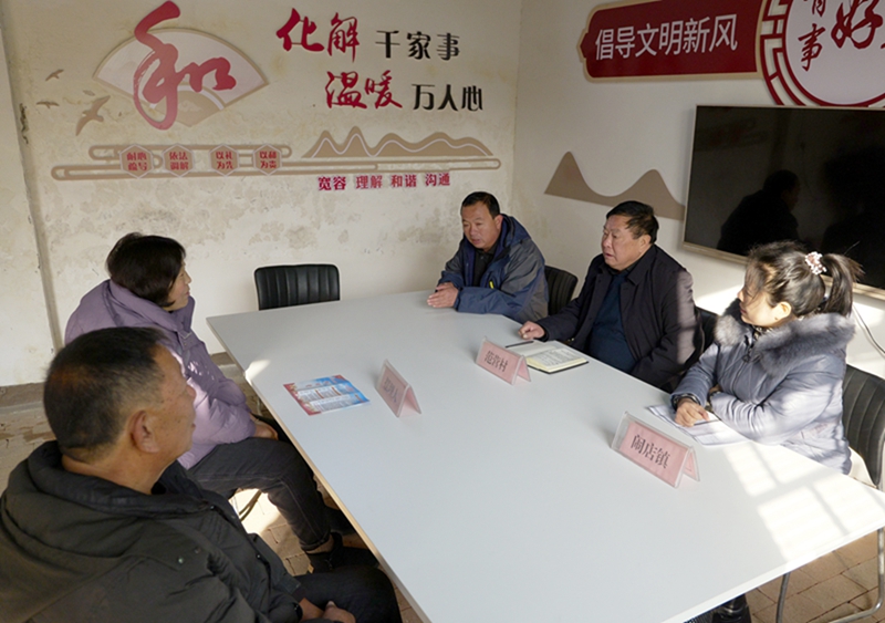 在宝丰县闹店镇范营村“摆理堂”，村镇干部（右）为村民进行信访调解（2023年12月20日摄）。